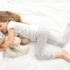 Little girl sleeping in bed with a teddy